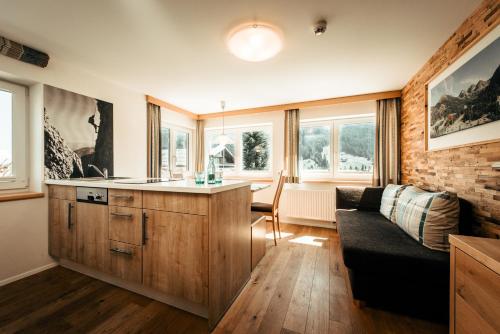 a living room with a couch and a kitchen at Ferienhotel Almajur in Mittelberg