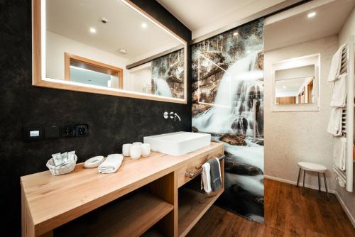 a bathroom with a sink and a mirror at Ferienhotel Almajur in Mittelberg