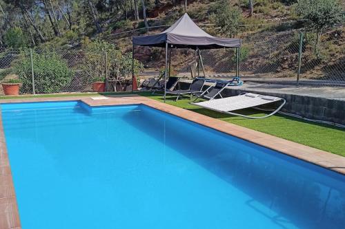 a large blue swimming pool with a tent and chairs at Masia La Roca in Castellnou de Bages