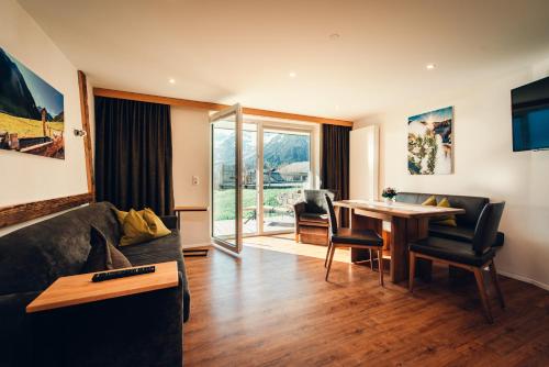 ein Wohnzimmer mit einem Sofa und einem Tisch in der Unterkunft Ferienhotel Almajur in Mittelberg