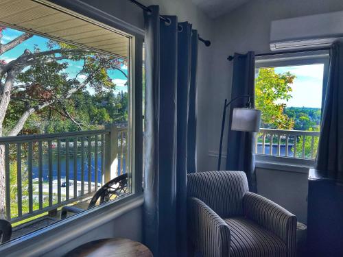 a room with a window with a chair and a balcony at Inn at the Falls in Bracebridge