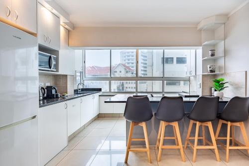 a kitchen with white cabinets and a large window at Perfect Beachfront Apartments in Cape Town