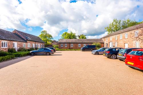 um parque de estacionamento com carros estacionados em frente a edifícios de tijolos em Wild Drive Chester - Stunning cottage in CH1 with Double Parking em Chester