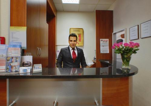 a man in a suit and tie sitting at a counter at Hotel Terminus am Hauptbahnhof & ZOB in Hamburg