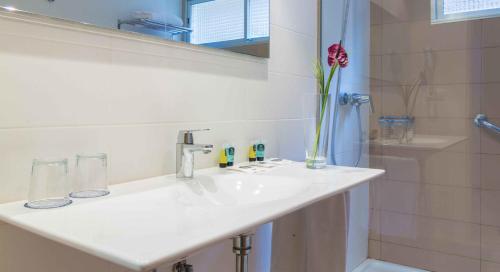 a bathroom with a sink and a vase with a flower at Hotel Albahia Alicante in Alicante