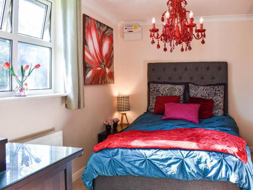 1 dormitorio con cama y lámpara de araña en Ace Lodge en Hoddesdon