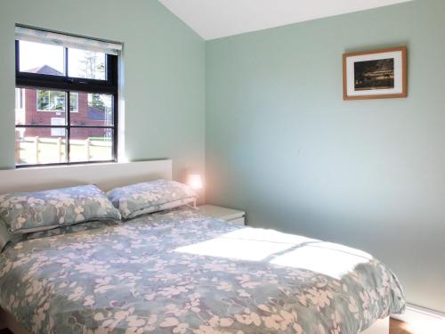 1 dormitorio con 1 cama con ventana y colcha en Cabin Hideaways, Glenfyne - Uk38362, en Mattishall