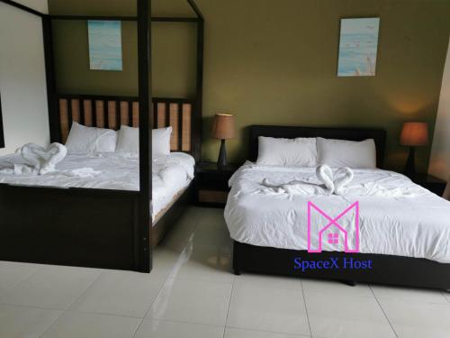 a bedroom with two beds with a synergy hotel sign on them at Gold Coast Morib Resort in Banting