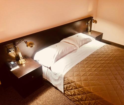 a bed in a hotel room with two night stands and two lamps at MOTEL Malpensa INN & Hotel-Airport in Tornavento