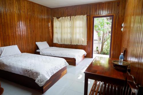 a bedroom with two beds and a table and a window at Song Lao Guesthouse in Thakhek