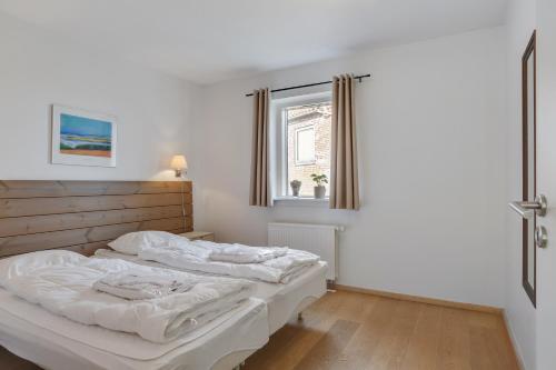 a white bedroom with a bed and a window at Skagen Harbour Apartments in Skagen