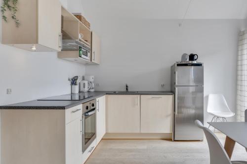 a kitchen with white cabinets and a stainless steel refrigerator at Skagen Harbour Apartments in Skagen
