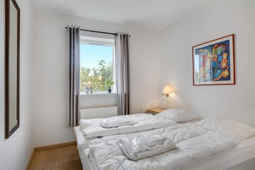 two beds in a white room with a window at Skagen Harbour Apartments in Skagen