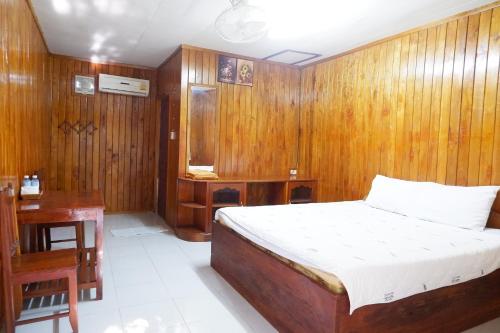a bedroom with a bed and a wooden wall at Song Lao Guesthouse in Thakhek