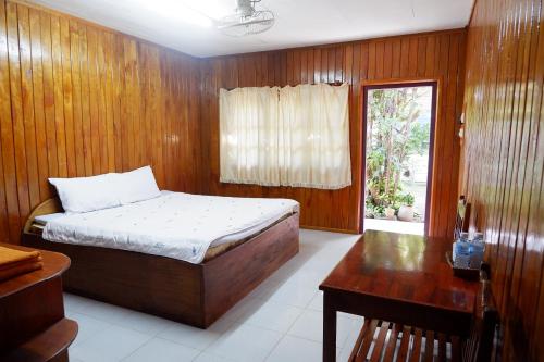 Song Lao Guesthouse في ثاكيك: غرفة نوم بسرير ومكتب ونافذة