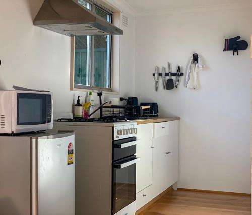 a kitchen with a stove and a microwave at Cosy guesthouse with private garden in Padstow