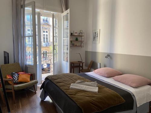 une chambre avec un lit, une chaise et une fenêtre dans l'établissement Bordeaux Palais Centre historique Balcon, à Bordeaux