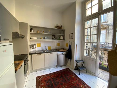une cuisine avec des placards blancs et une grande fenêtre dans l'établissement Bordeaux Palais Centre historique Balcon, à Bordeaux