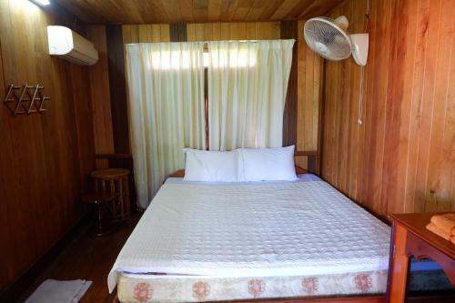 a bedroom with a bed in a wooden wall at Song Lao Guesthouse in Thakhek