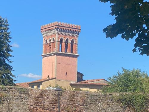 a building with a clock tower behind a brick wall at Il Rustico in Sansepolcro