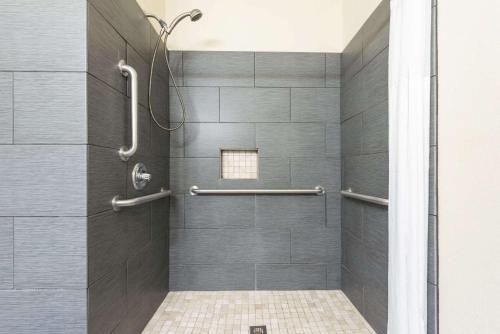 a shower with gray tiles and a glass door at Days Inn & Suites by Wyndham Prattville-Montgomery in Prattville