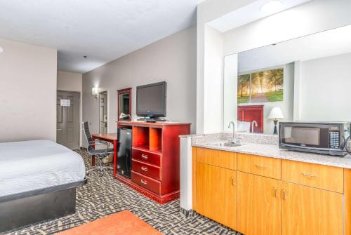 a hotel room with a bed and a kitchen with a sink at Days Inn & Suites by Wyndham Prattville-Montgomery in Prattville