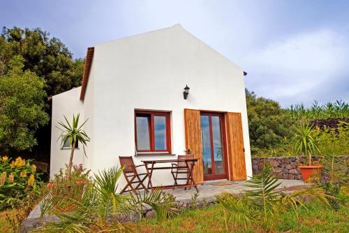 a small white house with a table and chairs at Casa Cachalote - Ferienhaus auf den Azoren in São Caetano