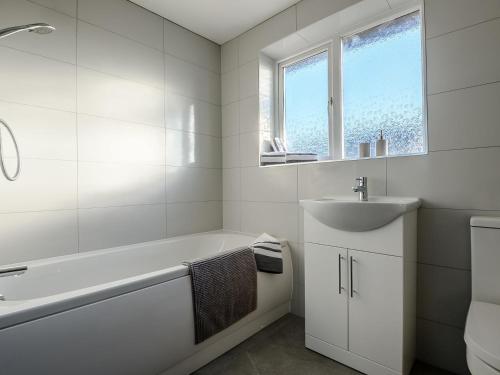 Baño blanco con bañera y lavamanos en Nightingale Lodge, en Ropsley