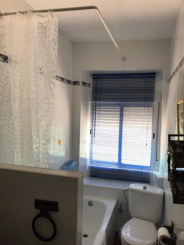 baño con aseo, bañera y ventana en Casa Belia en Mansilla de las Mulas