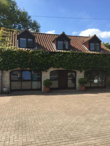 a house with ivy growing on the side of it at The Coach House at BYRE HOUSE in Coalpit Heath