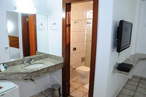 uma casa de banho com um lavatório, um WC e uma televisão em Panorama Tower Hotel em Ipatinga