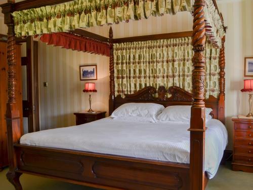 1 dormitorio con cama con dosel y sábanas blancas en Newstead, en Windermere