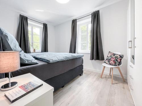 Schlafzimmer mit einem Bett, einem Stuhl und Fenstern in der Unterkunft Gut Groß Fedderwarden, Ferienwohnung Emma in Butjadingen