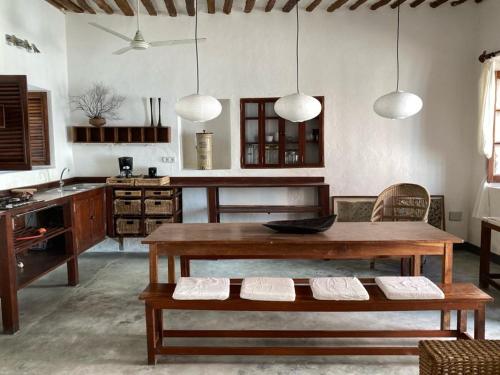 a living room with a table and a kitchen at Casa Fabula in Ilha de Moçambique