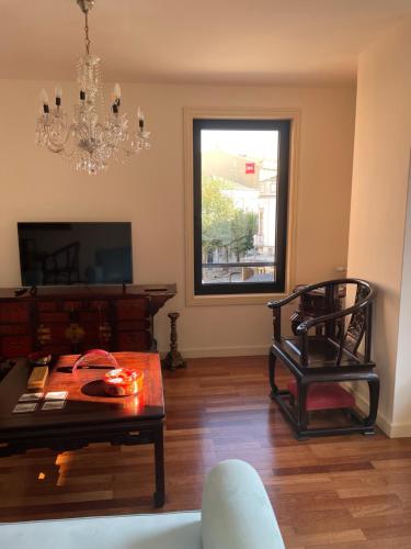 a living room with a table and a chair and a chandelier at Apartamento Mimi in Figueira da Foz