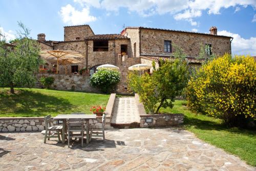 a stone house with a table and chairs in a yard at Romitorio di Serelle in Barberino di Val dʼElsa