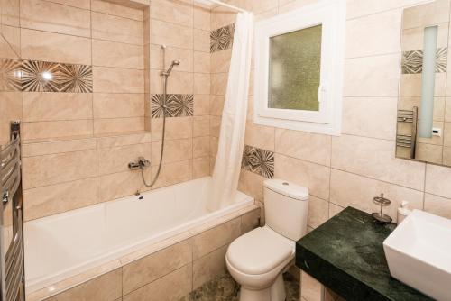 a bathroom with a toilet and a tub and a sink at Villa Gabriella Lefkada in Vafkeri