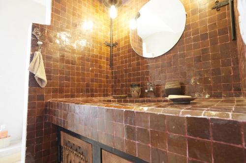 a brown tiled bathroom with a sink and a mirror at Kasbah Flilou in Aït Ougliff