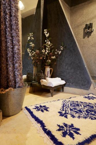 a bathroom with a blue and white rug and flowers at Kasbah Flilou in Aït Ougliff