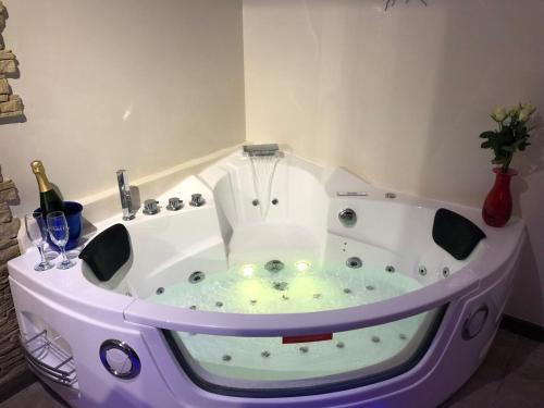 a jacuzzi tub in a room with a bottle of champagne at AUX PORTES DE LA CAMARGUE STUDIO BALNEO PISCINE in Tarascon