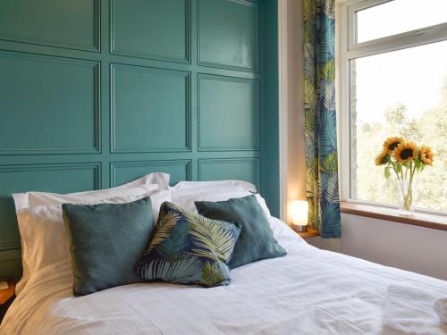 a bedroom with a bed with pillows and a window at Slant End Cottage in Golcar
