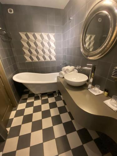 a bathroom with a tub and a sink and a mirror at Hôtel Gounod in Saint-Rémy-de-Provence