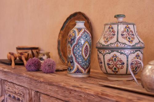 two vases sitting on a wooden table with a mirror at Kasbah Flilou in Aït Ougliff
