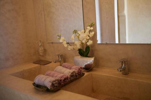 a bathroom sink with towels and a vase of flowers at Kasbah Flilou in Aït Ougliff
