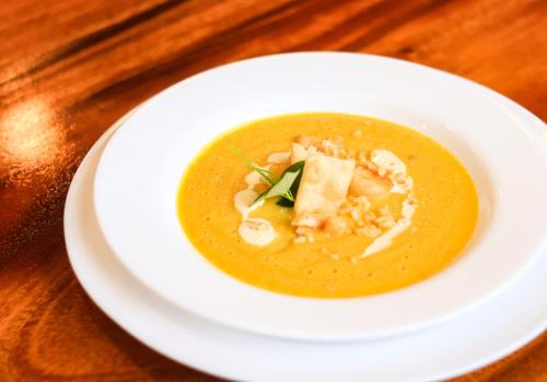 a white plate with a bowl of soup on a table at Josefina's Tourist Inn in Busuanga