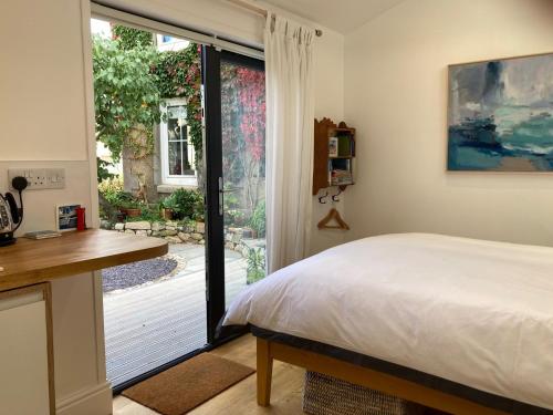 1 dormitorio con cama, escritorio y ventana en The Little Studio, en Penzance