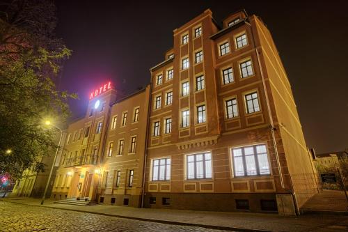 a building with a sign on top of it at night at Hotel Kamieniczka in Legnica