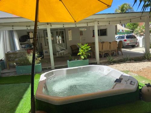 a hot tub with an umbrella in a yard at Luna 39 in Oranjestad