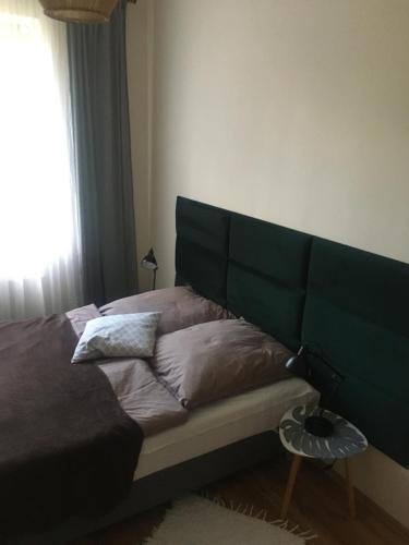 ein Bett mit einem grünen Kopfteil in einem Schlafzimmer in der Unterkunft Apartament M in Polanica-Zdrój