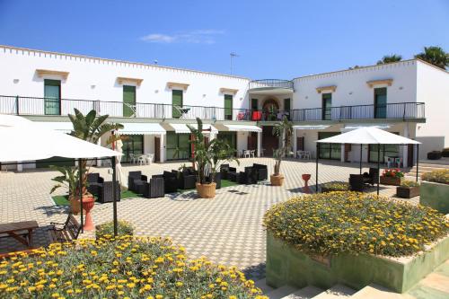 un hôtel avec des tables, des chaises et des parasols dans l'établissement Residence Cala Verde, à Marina di Mancaversa